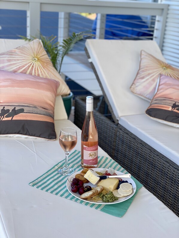 A table set with a bottle of wine, a glass, and a plate of cheese and fruits.