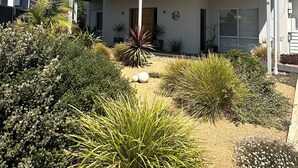 A two-story building with a covered patio area, surrounded by various shrubs and plants. - Room to relax in a perfect location with an easy walk to the beach and shops. (Normanville)