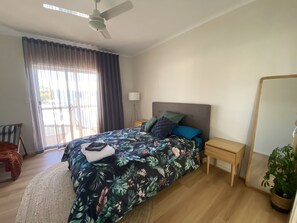 A bedroom with a bed, a nightstand, a lamp, a chair, a mirror, and a potted plant. - Room to relax in a perfect location with an easy walk to the beach and shops. (Normanville)