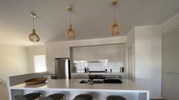 A modern kitchen with a central island, bar stools, and pendant lighting. - Room to relax in a perfect location with an easy walk to the beach and shops. (Normanville)