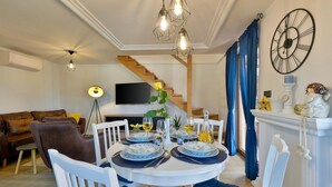 Een eethoek met een ronde tafel voor vier personen, een bank, een televisie en een trap.