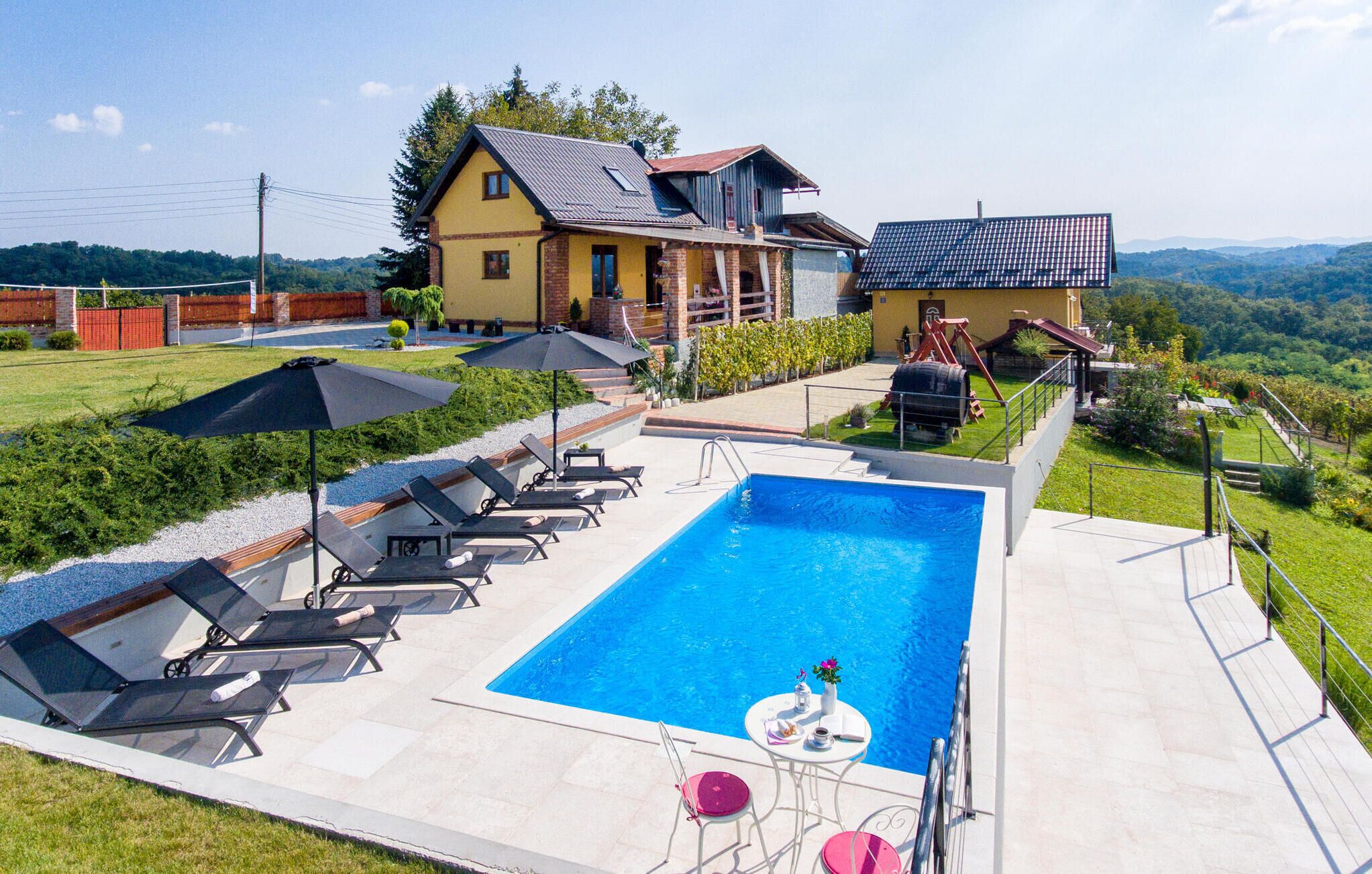 Une piscine entourée de chaises longues et d’une table, le tout bordé d’une pelouse bien entretenue, avec une maison en arrière-plan.