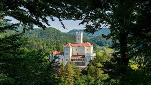 A castle with a prominent tower, surrounded by lush greenery and hills. - Beautiful home in Lepoglava with sauna (Lepoglava)