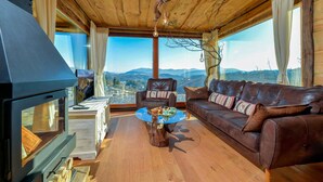 A cozy living room with a large wooden ceiling, a leather sofa, a glass coffee table, and a fireplace. - Beautiful home in Lepoglava with sauna (Lepoglava)