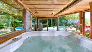 A hot tub in a wooden cabin with glass walls, a pool, and a garden view. - Beautiful home in Lepoglava with sauna (Lepoglava)
