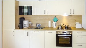 A compact kitchen with a microwave, coffee maker, kettle, toaster, and oven. - Cozy apartment in Malchow with WiFi (Malchow)