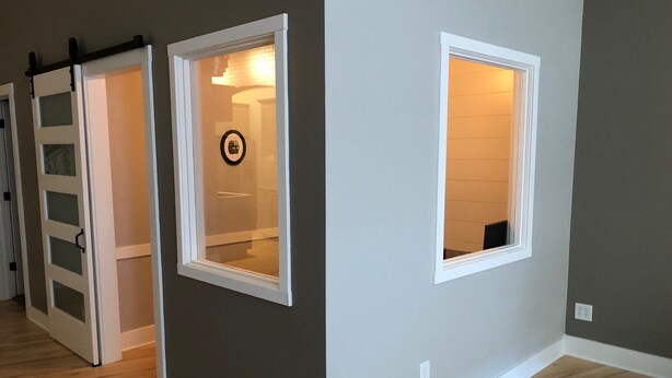 A room with a sliding door, a window with a picture frame, and a light fixture.