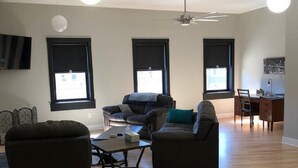 A spacious living room with a sofa, armchair, and a dining area with a table and chairs.