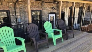 A wooden deck with Adirondack chairs and a stone wall.