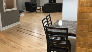 A modern living room with a fireplace, a dining area with a table and chairs, and a TV mounted on the wall.
