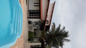 A swimming pool, a motorbike, a building with a tiled roof, and a palm tree. - Your best season in Gabriela's land (Ilhéus)