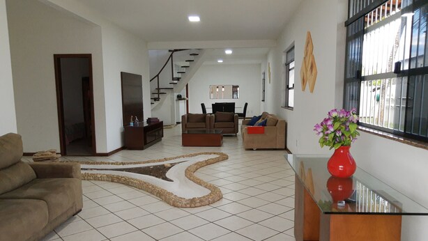 A spacious living room with a tiled floor, a staircase, and a large window with bars. - Your best season in Gabriela's land (Ilhéus)
