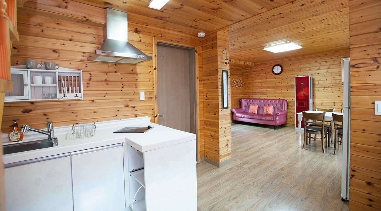 Un intérieur en bois comprenant une cuisine, un coin repas et un salon avec un canapé.