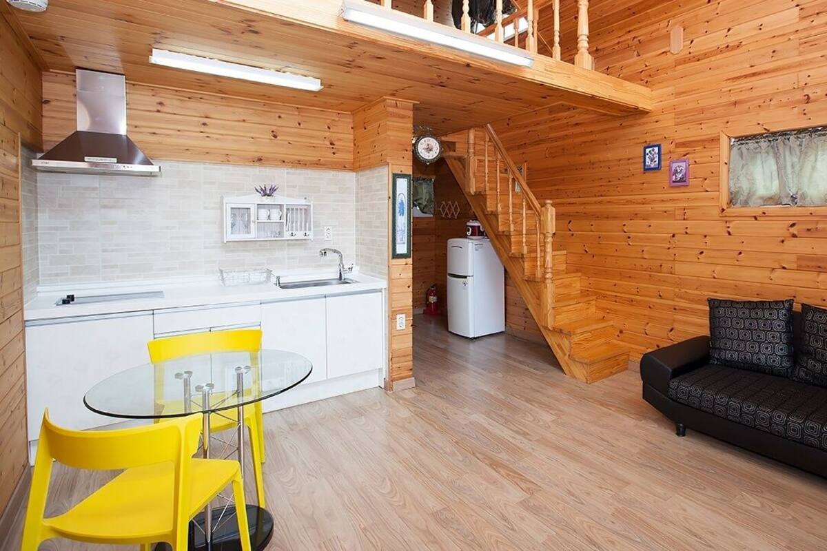 A wooden interior with a kitchen, dining area, and a sofa.