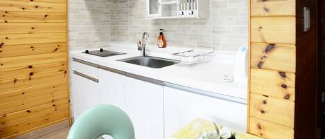 A compact kitchen with two sinks, a white cabinet, and a wooden wall.