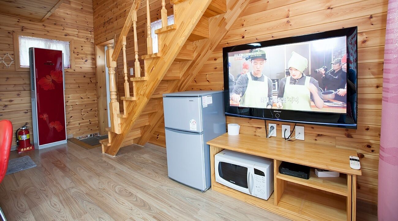 Un intérieur en bois avec une télévision, un four à micro-ondes et un réfrigérateur.