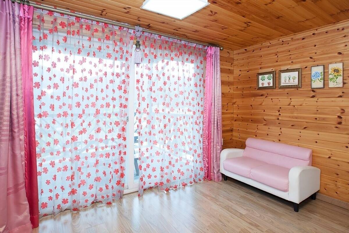 A room with wooden walls, a white sofa, and floral curtains.