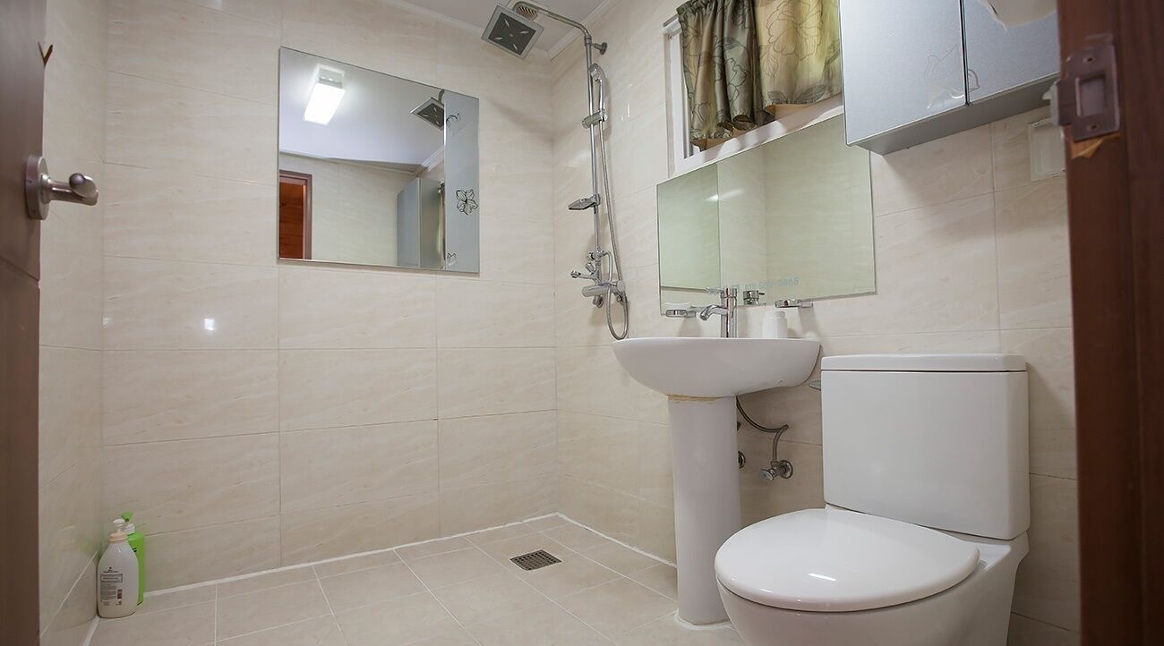 Une salle de bain équipée d’une douche, de toilettes, d’un lavabo et d’un miroir.
