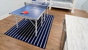 Ett rum med våningssängar, ett bord för bordtennis och en takfläkt.