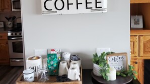 Uma bancada de cozinha com um espaço para café, incluindo um pote de café, açucareiro e café Starbucks.