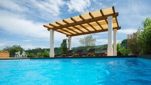 Une piscine agrémentée d’une pergola en bois, de chaises longues et d’un vélo.