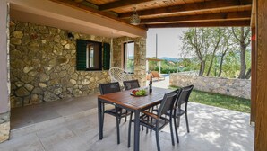 Une terrasse extérieure avec un mur en pierre, une table en bois et des chaises.