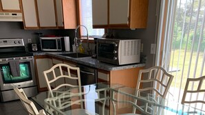 Une cuisine moderne avec une table à manger en verre, des chaises blanches et des appareils électroménagers intégrés.