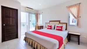 A hotel room with a large bed, two bedside tables, a window with curtains, an air conditioning unit, and a door. - OYO 605 Lake View Phuket Place (Ratsada)