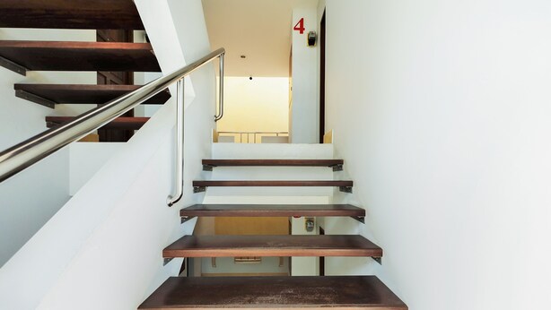 A staircase with wooden steps and metal handrails, leading to a landing with a door marked with the number 4. - OYO 605 Lake View Phuket Place (Ratsada)