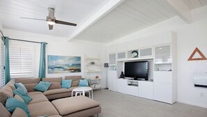 Uma sala de estar moderna com um sofá seccional, uma TV de tela plana e estantes embutidas.