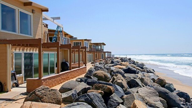 Um hotel à beira-mar com edifícios de vários andares, grandes janelas e uma costa rochosa.