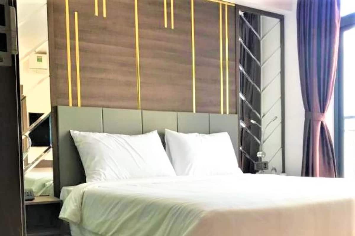 A hotel room with a bed, a nightstand, a wardrobe, and a window with curtains.