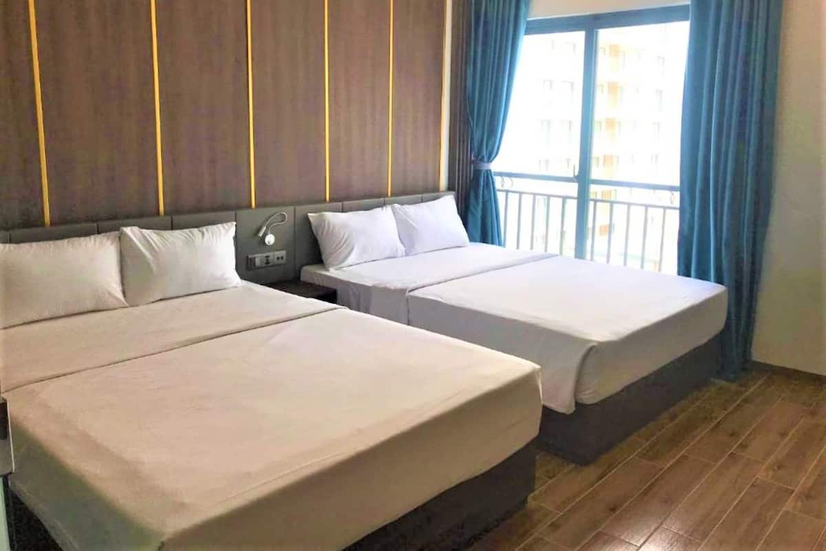 A hotel room with two beds, a nightstand, and a window with curtains.