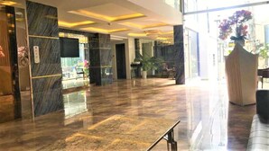 En moderne lobby med marmorgulv, en receptionsdisk og et stort vindue med udsigt til gaden.