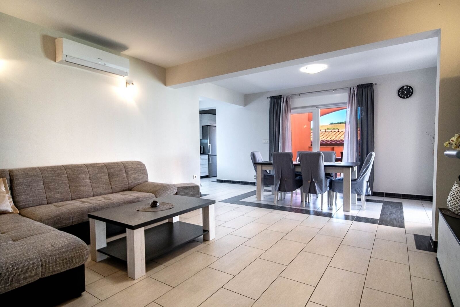 A modern living room with a sofa, coffee table, and dining area with chairs and a table.