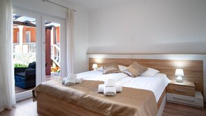 Ein Hotelzimmer mit einem großen Bett, zwei Nachttischen, einem hölzernen Kopfteil und Blick ins Freie.