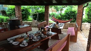 Eine Terrasse im Freien mit Steinfliesen, Holztischen und Bänken.