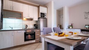 Una cocina moderna con armarios de madera, horno empotrado y comedor con desayunador.