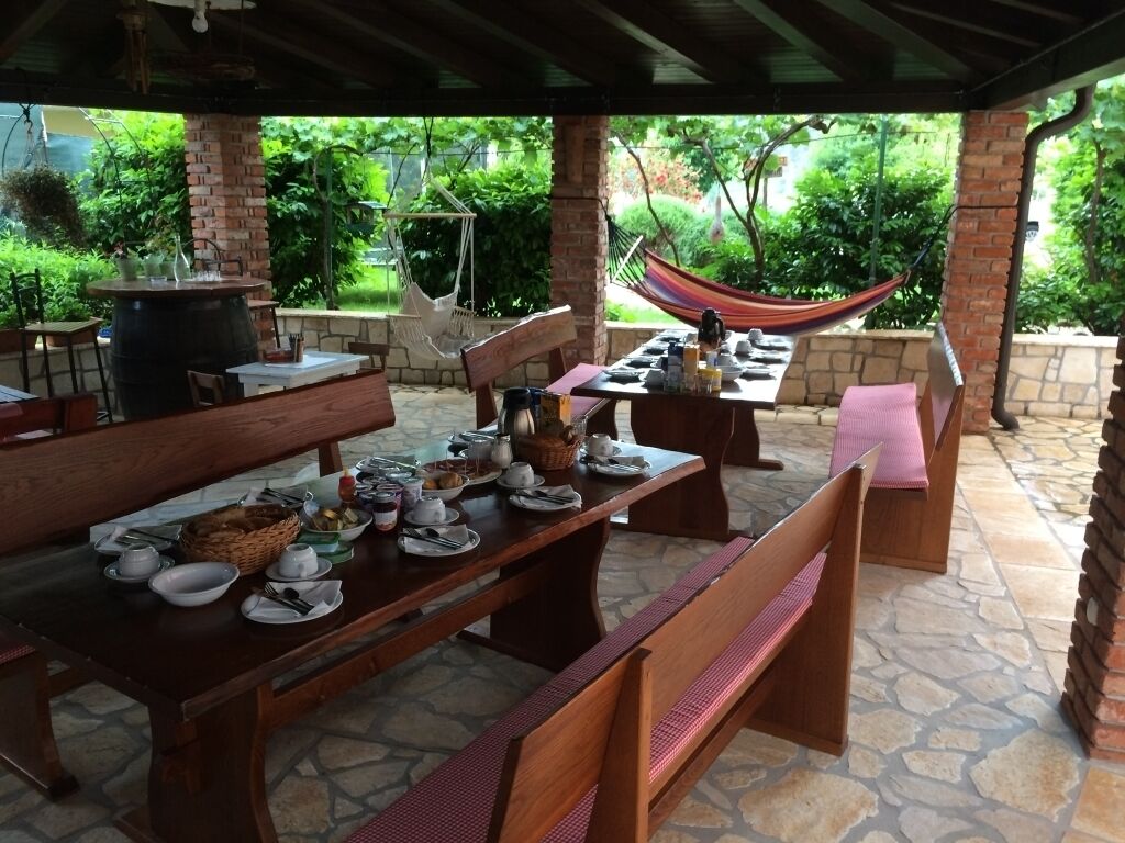 An outdoor patio with stone flooring, wooden tables, and benches.