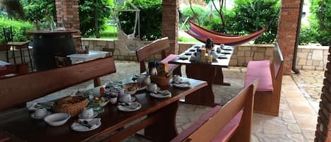 An outdoor patio with stone flooring, wooden tables, and benches.