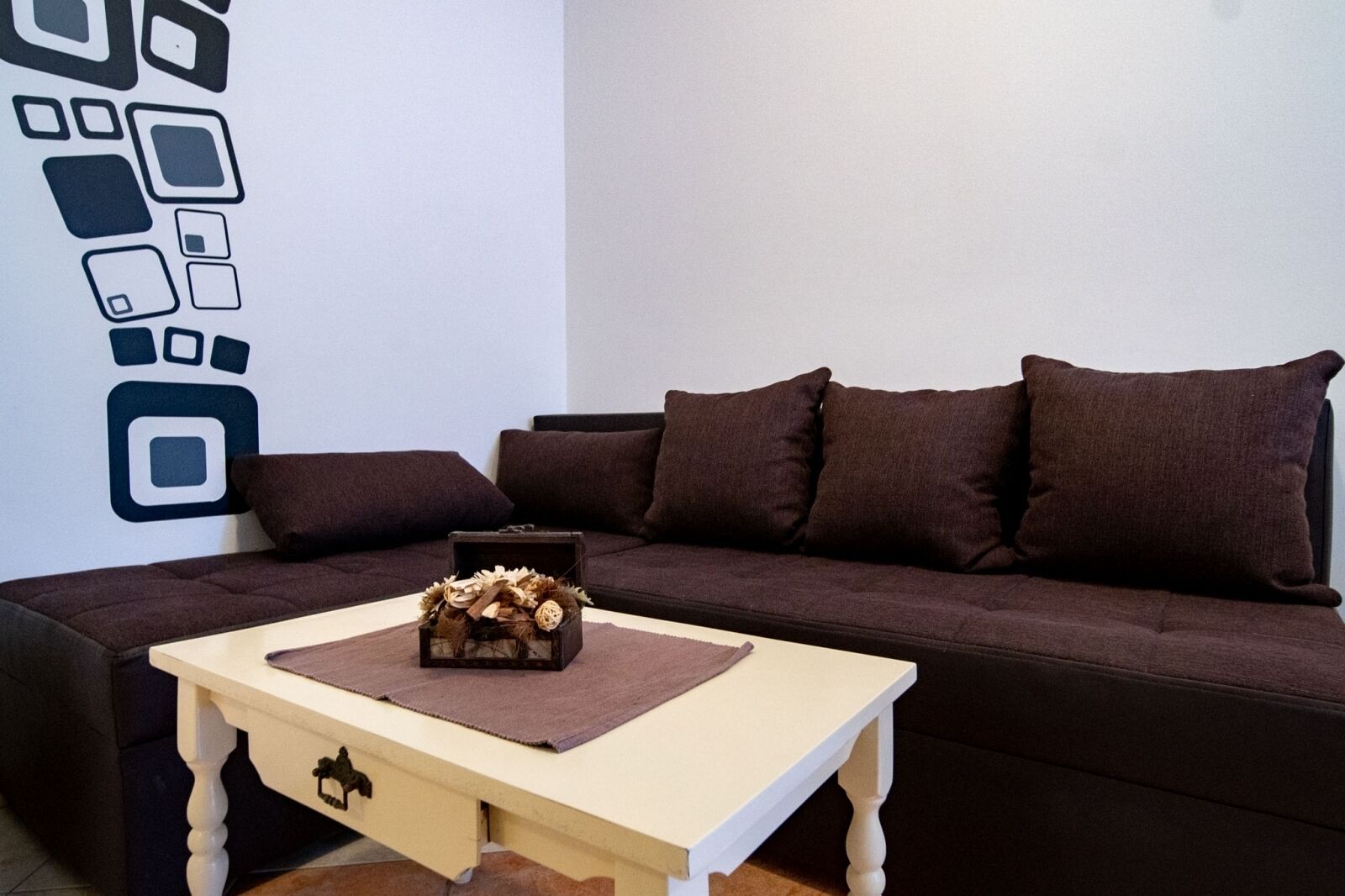 A living room with a brown sofa, a small wooden table, and a decorative box on the table.