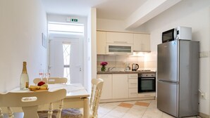 A modern kitchen with a refrigerator, oven, and microwave. There is a dining table with chairs and a bottle of wine. - Apartment in Lopar with Terrace, Air condition, WIFI, Washing machine (4885-4) (Lopar)