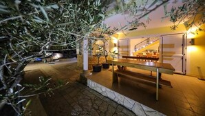 An outdoor patio area with a wooden bench, potted plants, and a staircase leading to an upper level.