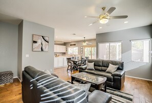 Uma sala de estar moderna com um sofá, mesa de centro e uma área de jantar ao fundo.