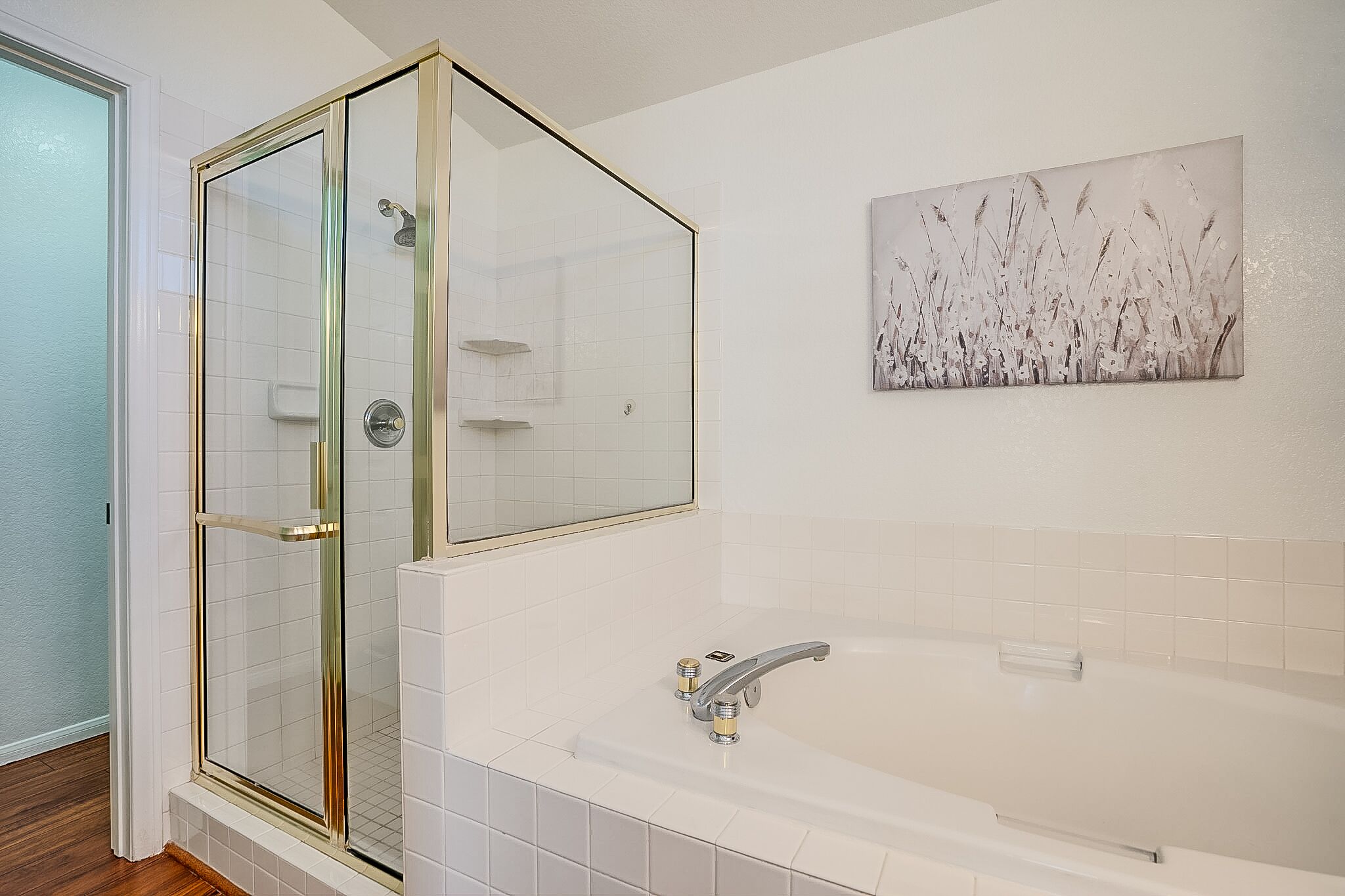 A modern bathroom with a glass-enclosed shower, a freestanding bathtub, and a wall-mounted artwork.