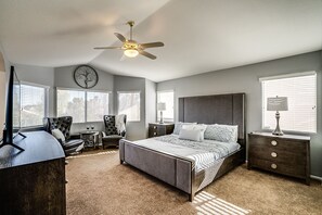 Quarto com cama, mesa de cabeceira, cadeira, abajur e ventilador de teto.