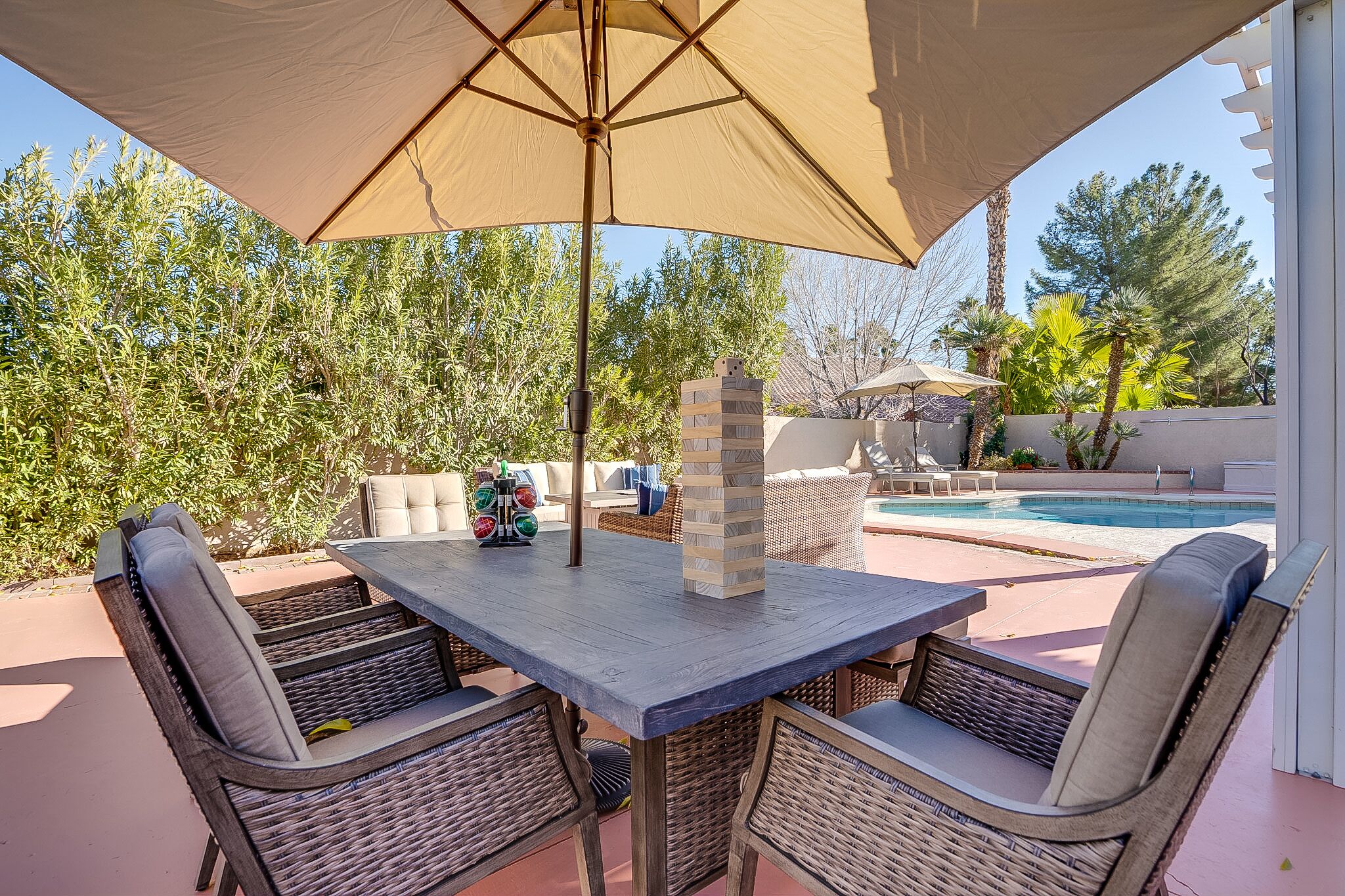 An outdoor patio with a table, chairs, and a large umbrella.
