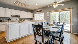 A modern kitchen with white cabinets, a large island, and a dining area with a table and chairs.