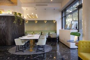 A modern dining area with a marble floor, a round table with chairs, pendant lights, and a view of the outdoors through large windows. - Quinzerie Hotel (Paris)