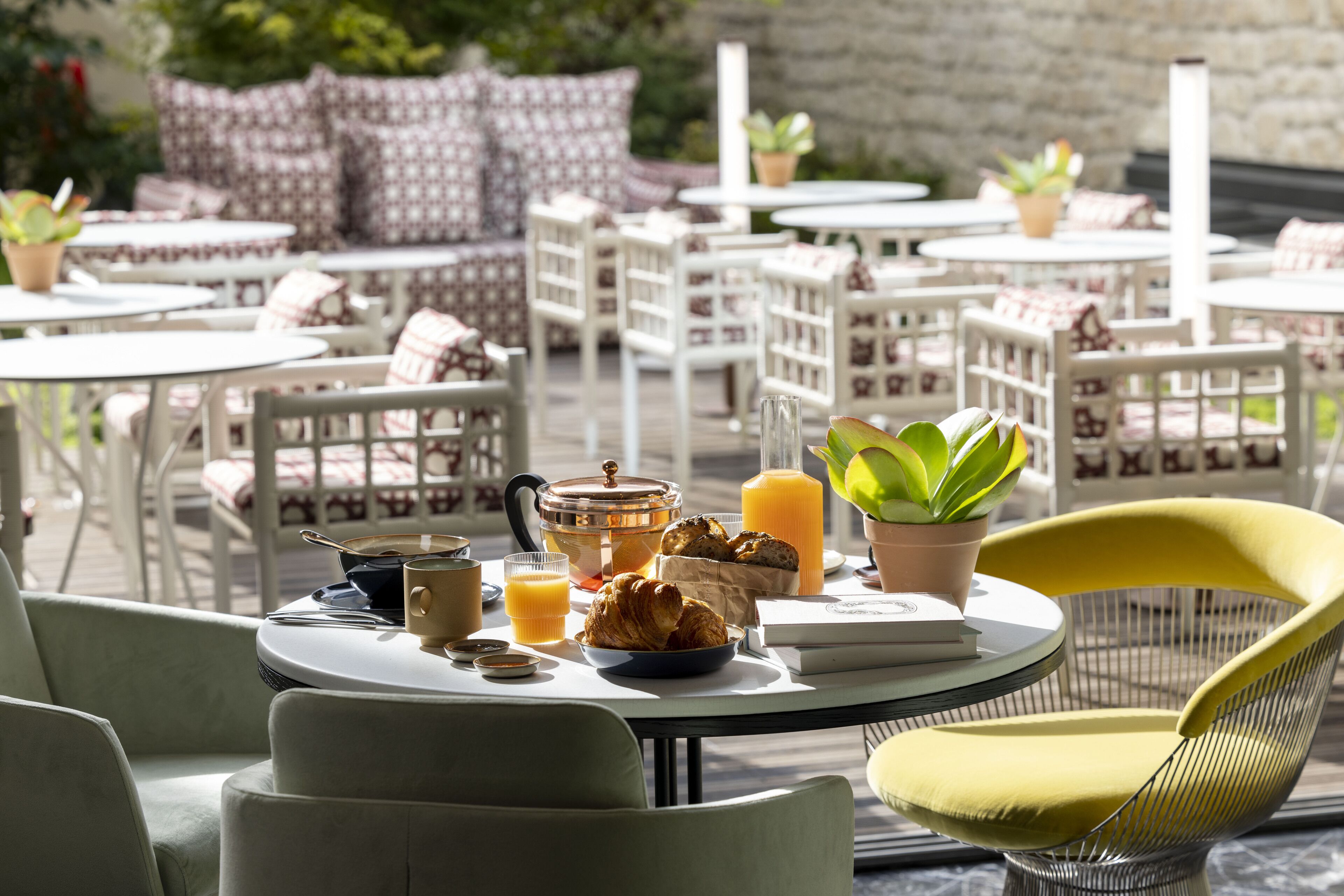 A breakfast setup with a table, chairs, and a variety of food and drink items.